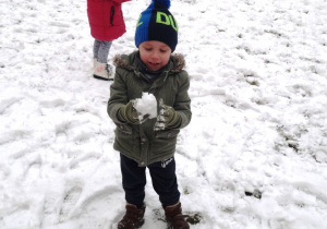Chłopiec lepi kulkę ze śniegu